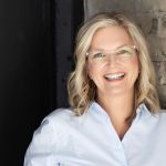 blond white woman with glasses smiling