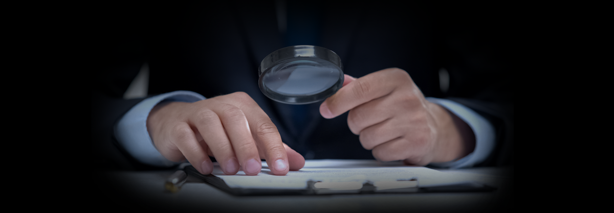 Photo of hands using a magnifying glass over paper.