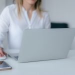 Woman in white shirt works on a computer. Image by Marek Levak via Pexels.