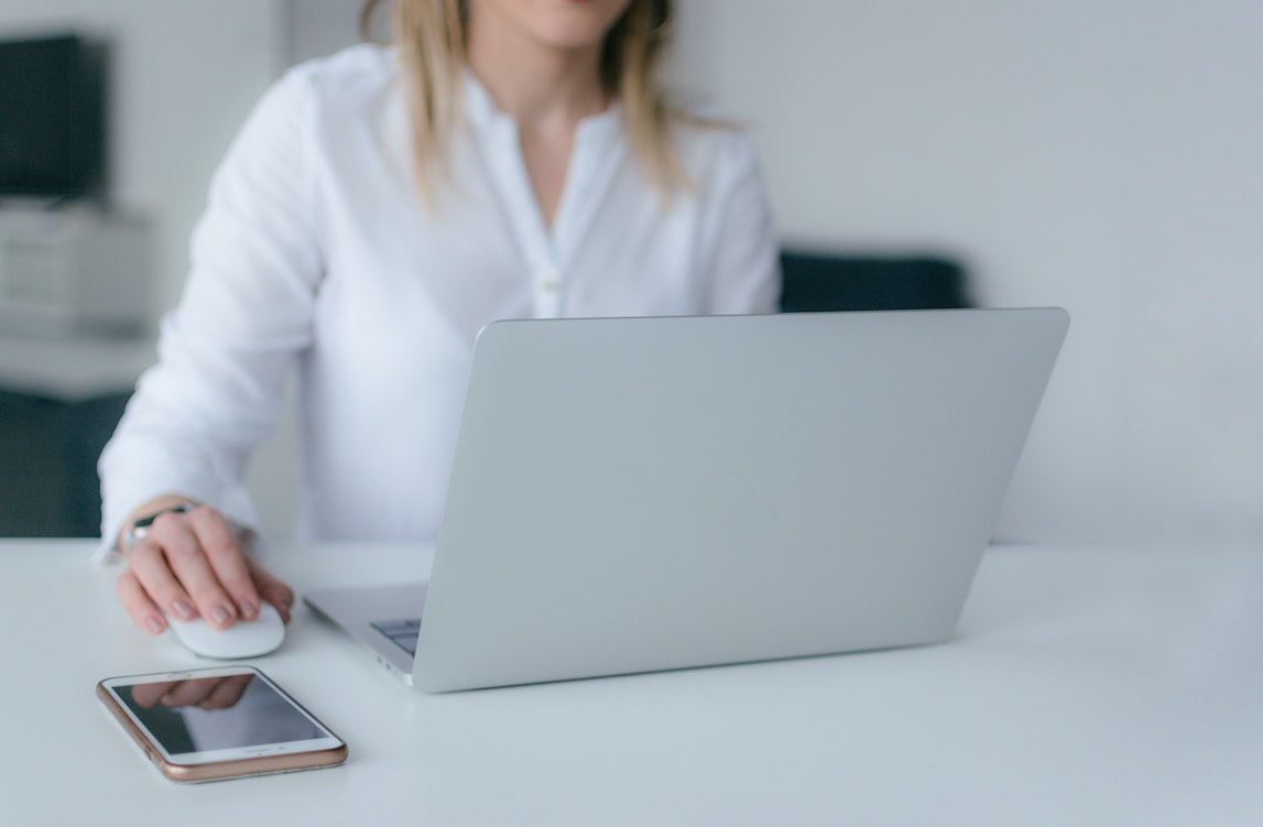 Woman in white shirt works on a computer. Image by Marek Levak via Pexels.