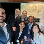A group of students smiling in front of their capstone project poster
