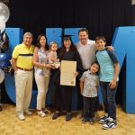 Photo of a graduate with her certificate and her family.