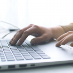 Hands typing on a laptop