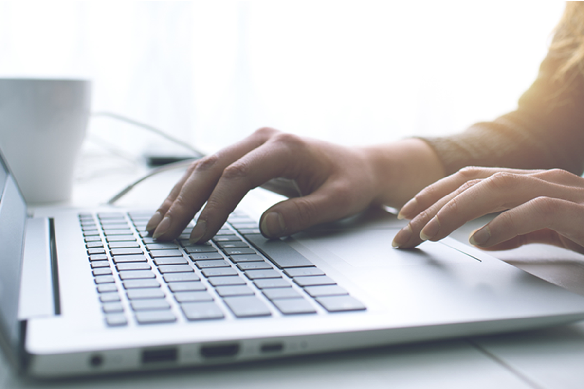 Hands typing on a laptop