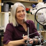 Dr. Kristine Cowley in her lab. A large piece of scientific equipment is in the foreground.