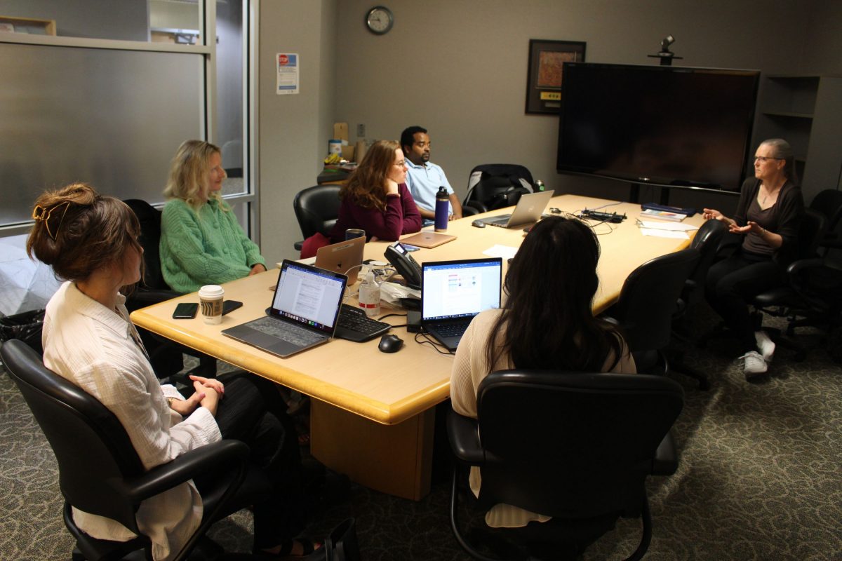 Six people sit around a meeting-room table.