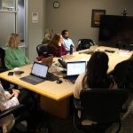Six people sit around a meeting-room table.
