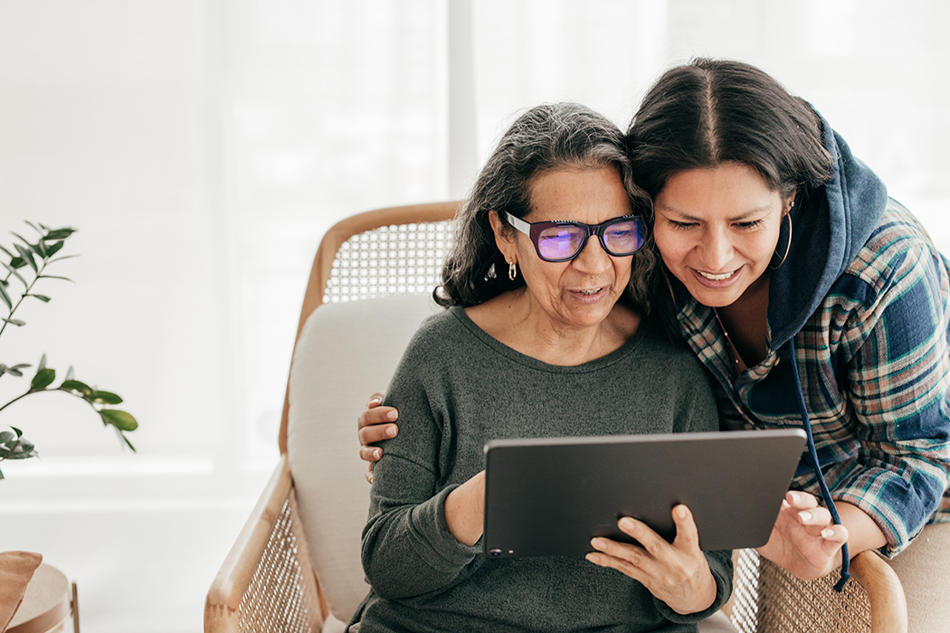 An adult daughter caring for her older mother, looking at a computer tablet screen.