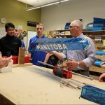 people in workshop looking at airplane parts
