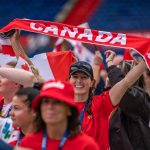 Canadian athletes waving banners coming into a stadium at the World Police and Fire Games opening ceremonies in Rotterdam in summer 2022