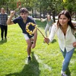 Students playing traditional Indigenous games in an outdoor green space.