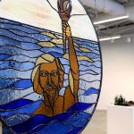 Gallery image of a stained glass circle depicting a man with his arm raised.