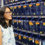 Sophie Chen looks at small fish tanks containing zebrafish. There are dozens of tanks in the room.