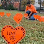 Orange hearts with messages for truth and reconciliation "planted" in a grassy field.