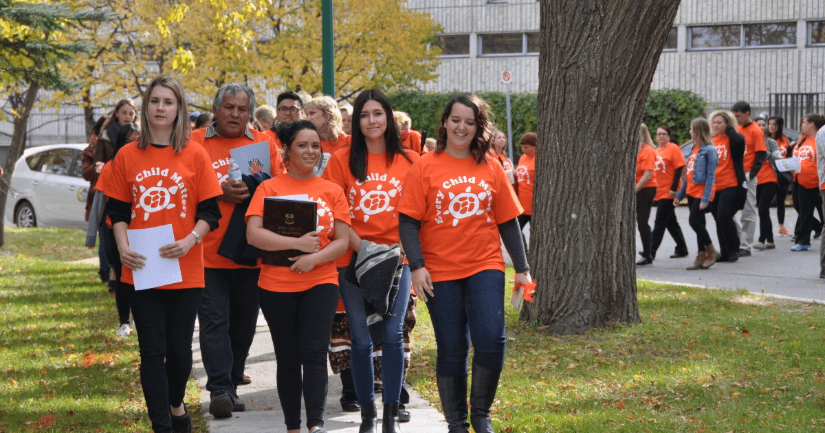A group of people wearing orange t-shirts march toward the camera.