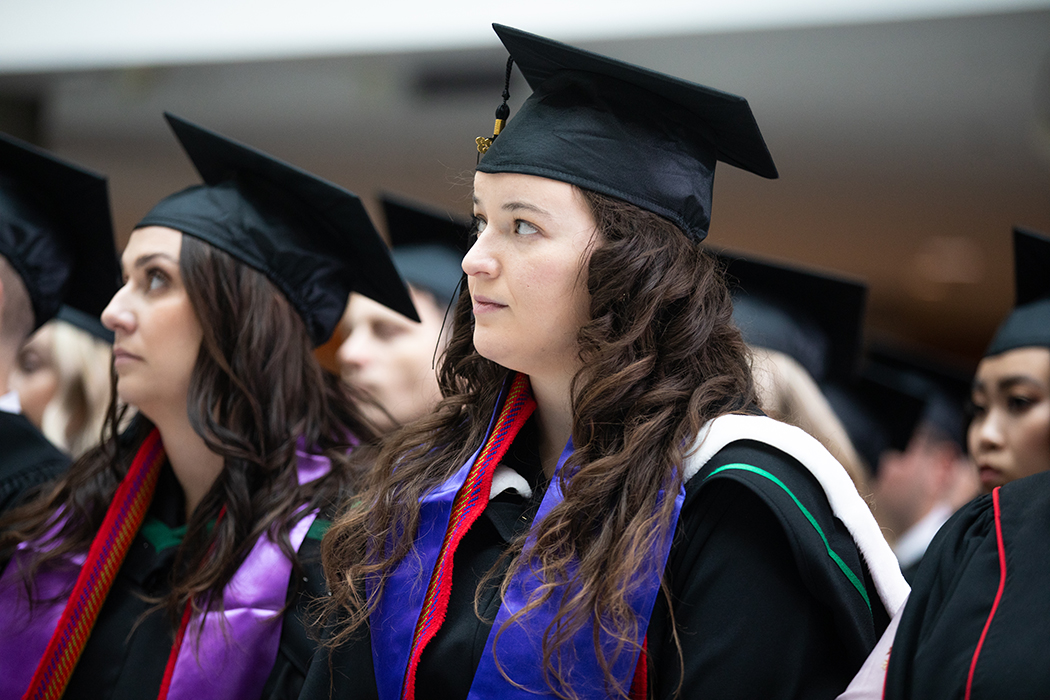 Kaylene Normand in her cap and gown, wearing an Indigenous sash, at convocation.
