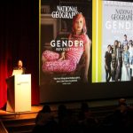 Dr. Brandy Wicklow speaks at the WISDOM Symposium beside a projected slide on the theme of "gender revolution."