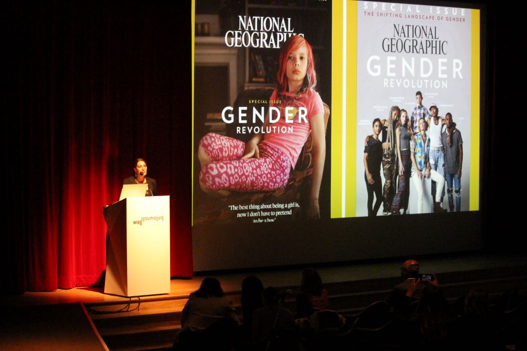 Dr. Brandy Wicklow speaks at the WISDOM Symposium beside a projected slide on the theme of "gender revolution."