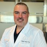 Dr. Waylon Hunt wearing a white lab coat.