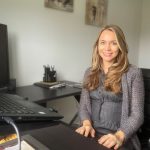 Dr. Ana Ludke sits at a desk with her hands on the computer keyboard.