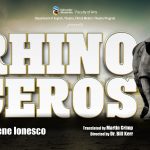 A rhinoceros standing next to large, white letters spelling the word rhinoceros.