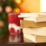 image of books stacked up with mug and holiday lights out of focus.
