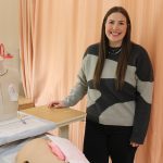 A nursing student posing at a simulation lab bedside.