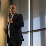 Gordon Giesbrecht presents with a microphone in hand