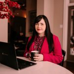 Tammy Stuart Chester sits at a table with a laptop computer open in front of her.