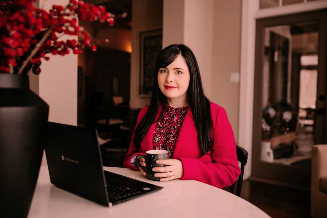 Tammy Stuart Chester sits at a table with a laptop computer open in front of her.