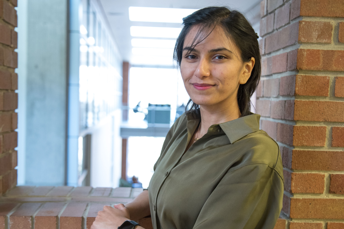 Azadeh Tabiban smiling and leaning against a brick window.