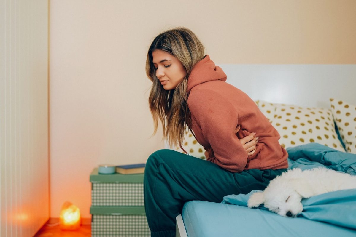 Young woman clutches her abdomen in pain.