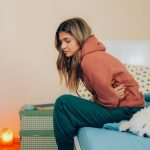 Young woman clutches her abdomen in pain.