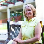 Diana McMillan sitting outside the College of Nursing on a summer day.