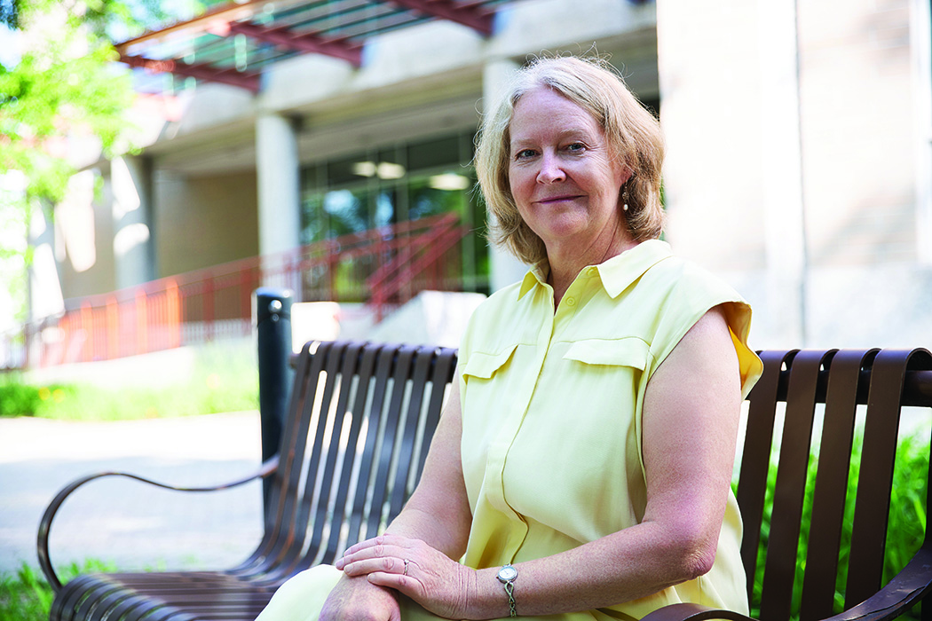 Diana McMillan sitting outside the College of Nursing on a summer day.