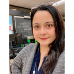 student with long dark hair and glasses taking a selfie