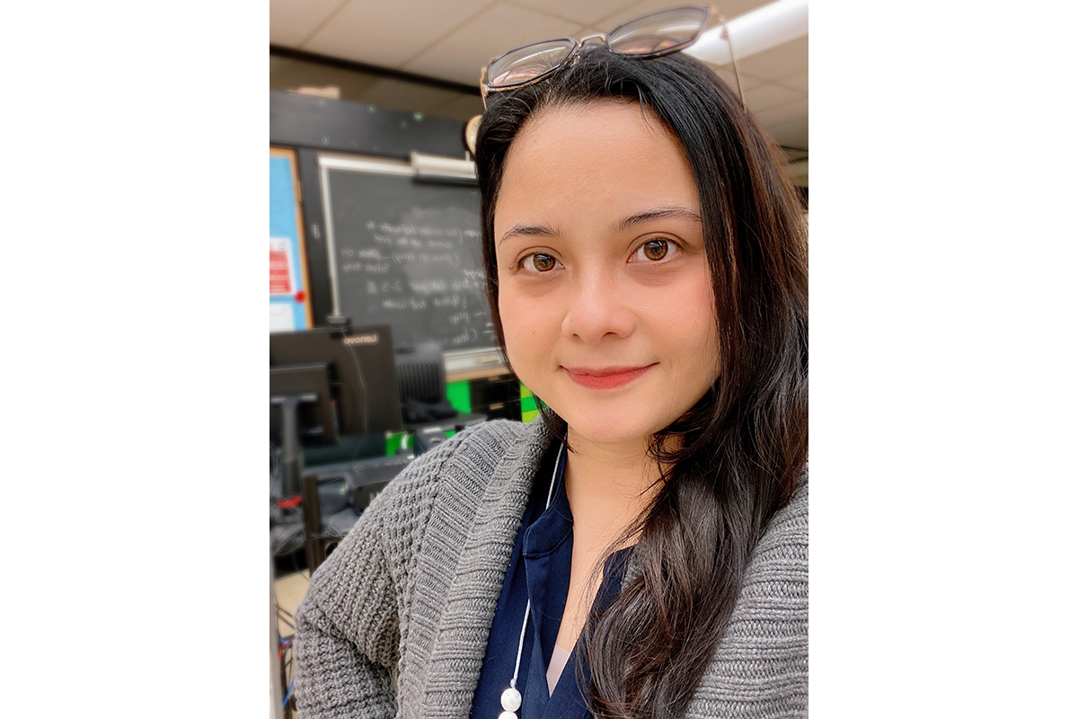 student with long dark hair and glasses taking a selfie