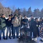 A group standing on the quad smiling with hot chocolate