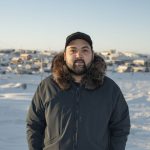 Inuk man stands outside in Northern community