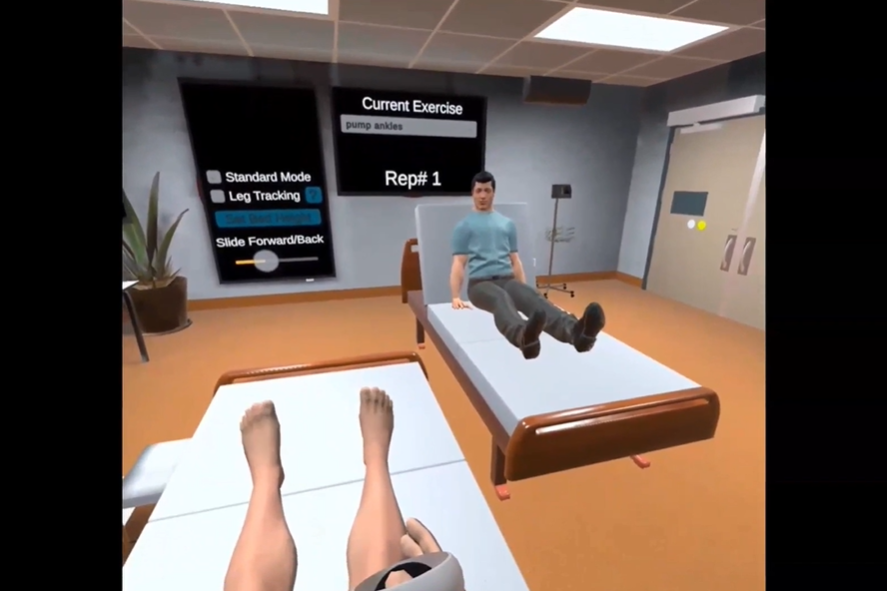 In clinical setting, user is sitting on a bed with legs extended and one hand in frame. An avatar sits on a bed across from the user. Text in two boxes on screen reads: "Standard mode. Leg tracking. Slide forward/back. Current Exercise. Pump ankles. Rep# 1."