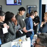 Students discuss career options with a professional at a career fair booth.