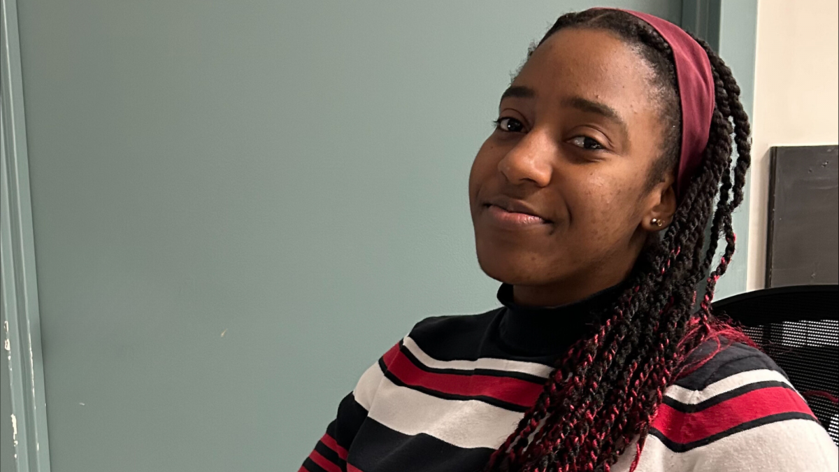 Photo of Munashe Nhunzwi, a Black student with a red and white sweatshirts on, smiling at the camera.