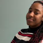 Photo of Munashe Nhunzwi, a Black student with a red and white sweatshirts on, smiling at the camera.