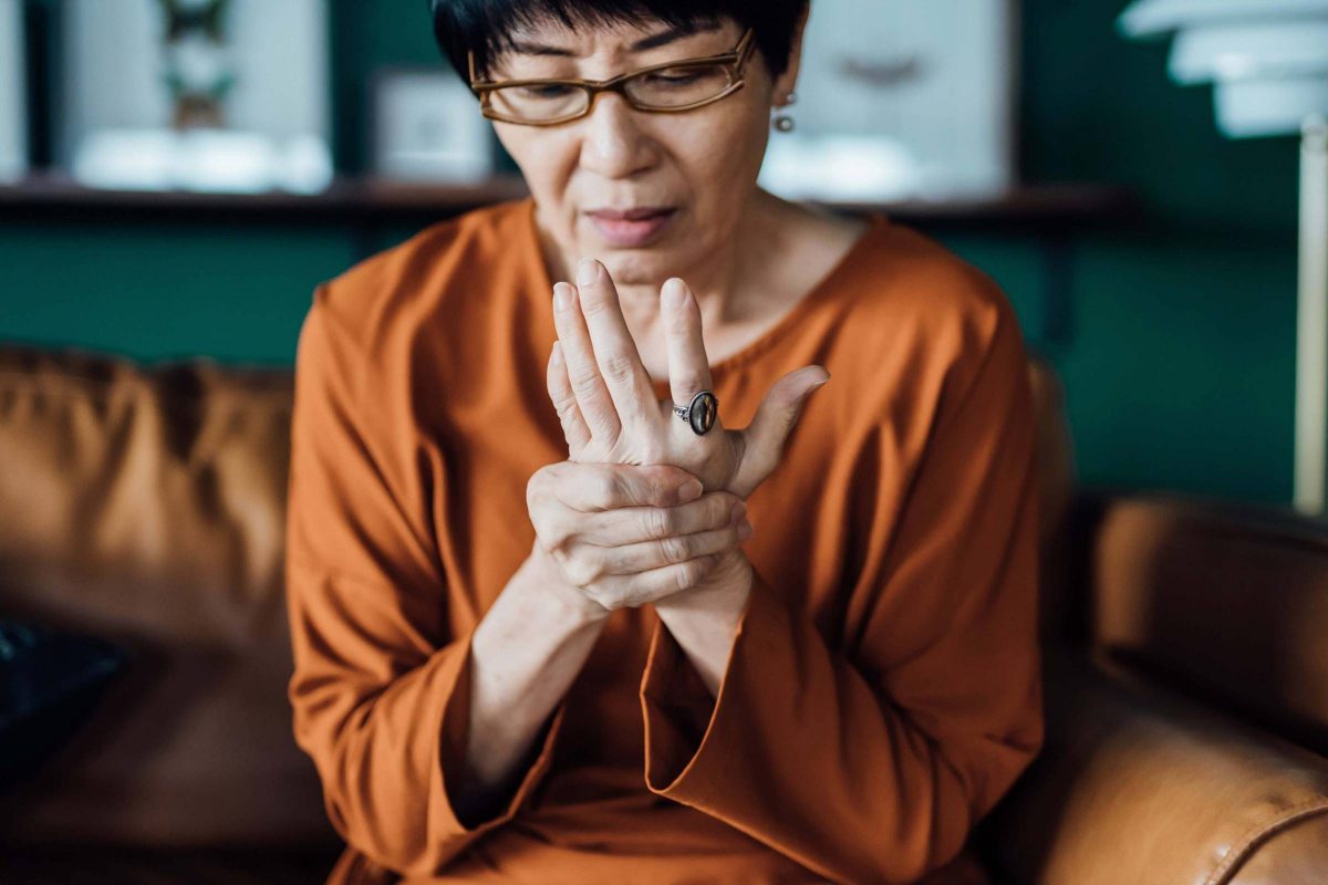 A woman rubs her hands and looks distressed, as if they are sore.