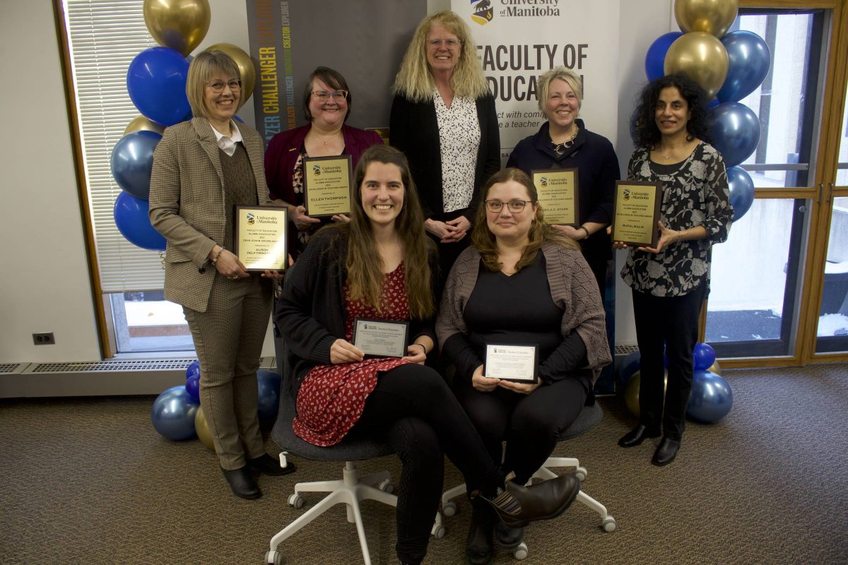 alumni awards recipient posing for photo next to Faculty of Education banners