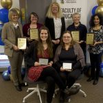 alumni awards recipient posing for photo next to Faculty of Education banners