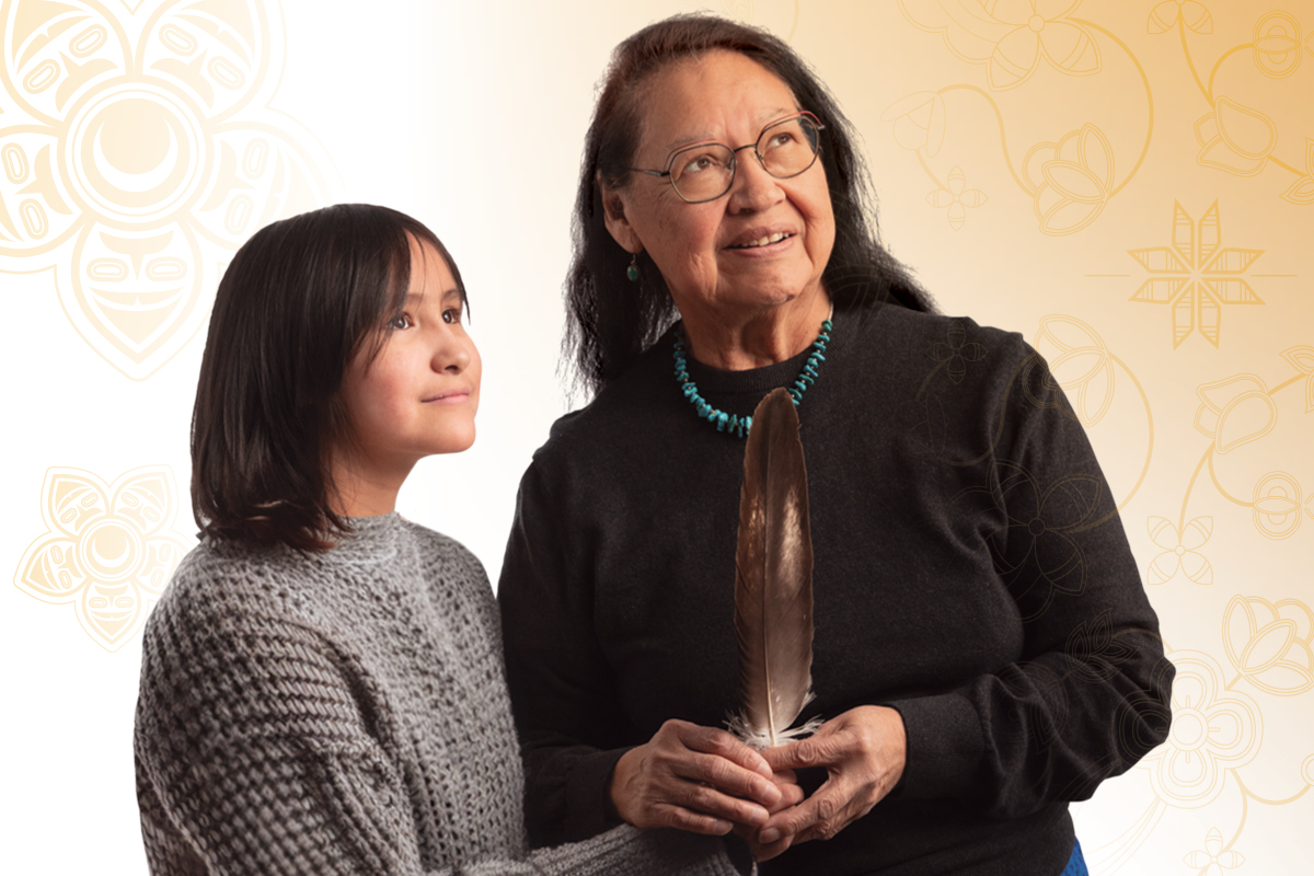 An Indigenous grandmother and her granddaughter holding a feather.