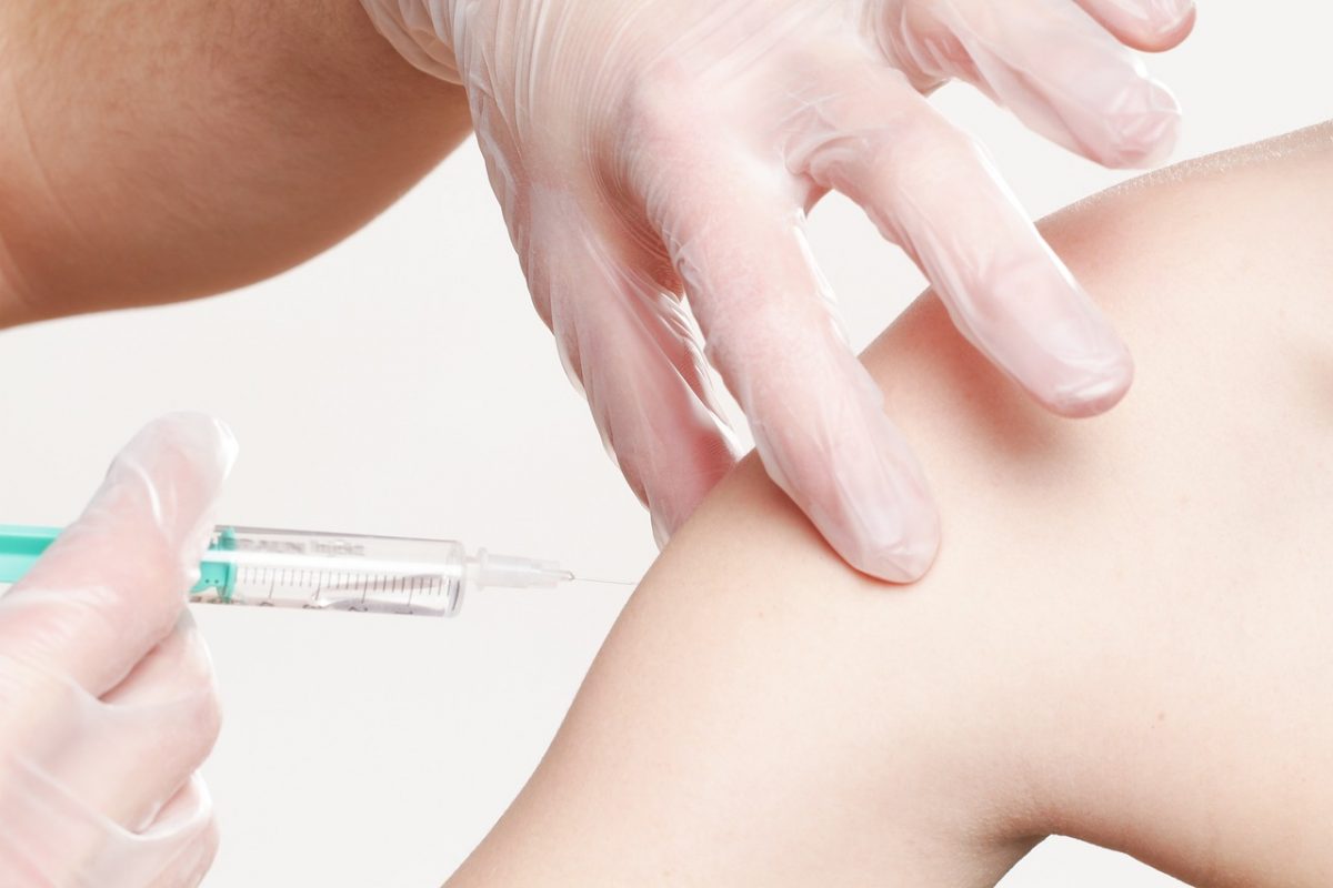 A vaccination being delivered into an arm via a needle.