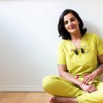 Huma Sharief sits crosslegged on the floor, leaning against the blank wall of her condo
