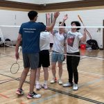 a group of badminton players high-fiving after a game